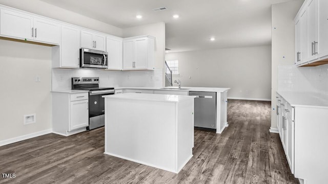 1009 Ocean Ct, Carthage, NC 28327 - kitchen with appliances with stainless steel finishes, a peninsula, dark wood-style flooring, backsplash, and white cabinetry