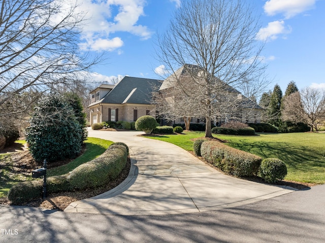 view of front of house featuring concrete driveway, brick siding, and a front lawn