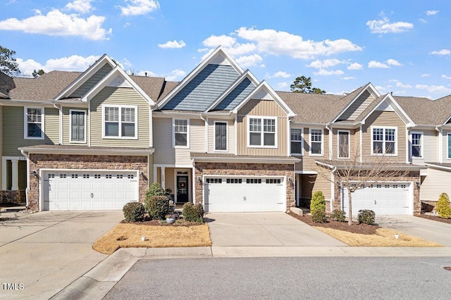 view of property featuring a garage, stone siding, and driveway