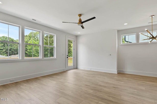 unfurnished room featuring ceiling fan with notable chandelier and light wood-type flooring