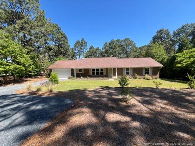 ranch-style home featuring a porch, a garage, a front lawn, and driveway