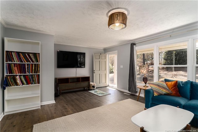 living room with crown molding, a textured ceiling, baseboards, and wood finished floors