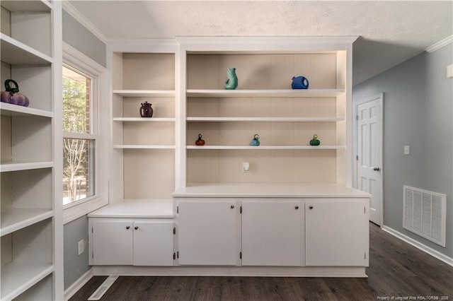 interior space with baseboards, wood finished floors, and visible vents