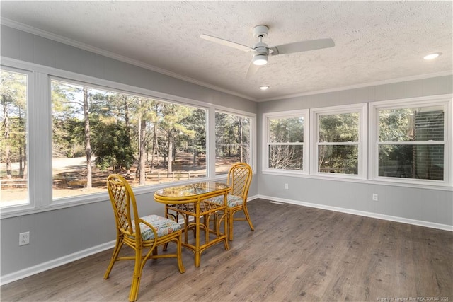 sunroom / solarium featuring a textured ceiling, wood finished floors, and a healthy amount of sunlight