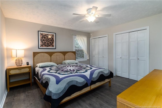 bedroom with a textured ceiling, multiple closets, ceiling fan, and dark wood-style floors