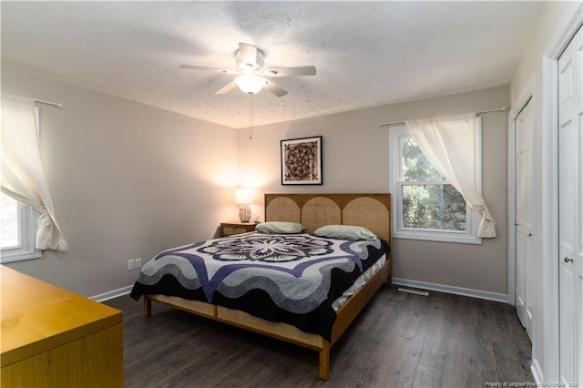 bedroom with a textured ceiling, baseboards, a ceiling fan, and dark wood-type flooring