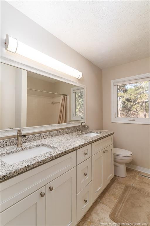 bathroom with double vanity, toilet, visible vents, and a sink