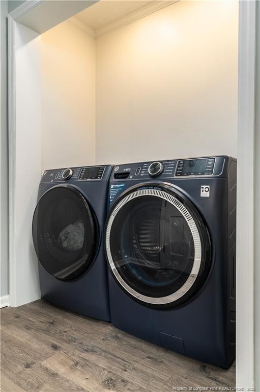 laundry room featuring independent washer and dryer, crown molding, wood finished floors, and laundry area