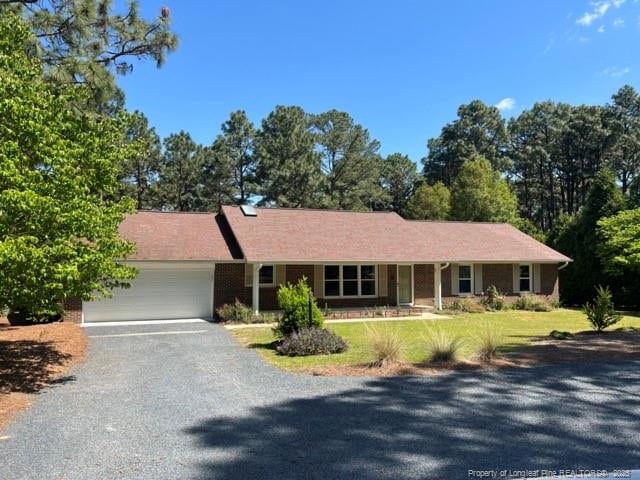 ranch-style house featuring an attached garage, driveway, and a front lawn