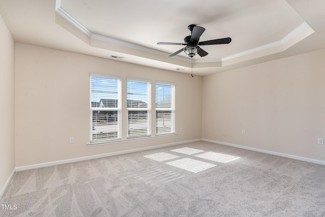 empty room with ornamental molding, a raised ceiling, and light colored carpet