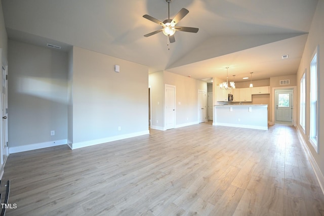 unfurnished living room featuring ceiling fan with notable chandelier, light hardwood / wood-style flooring, and vaulted ceiling