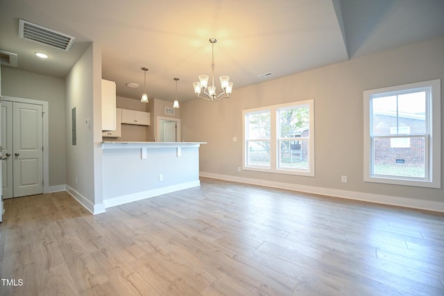 kitchen featuring a breakfast bar, light wood-type flooring, white cabinetry, pendant lighting, and kitchen peninsula