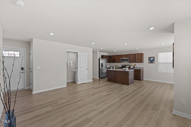 kitchen featuring light wood-style floors, open floor plan, light countertops, appliances with stainless steel finishes, and a center island