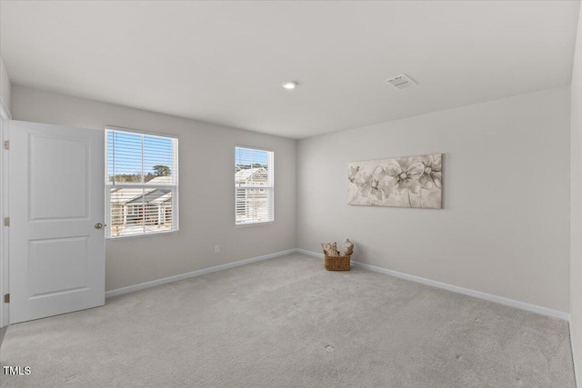 spare room with light carpet, visible vents, and baseboards