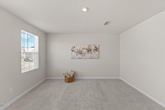 unfurnished room with baseboards, visible vents, and light colored carpet