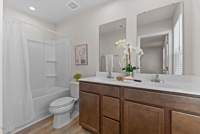 full bathroom with double vanity, visible vents, a sink, and wood finished floors