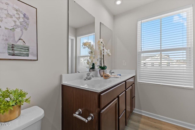 bathroom with toilet, baseboards, wood finished floors, and vanity