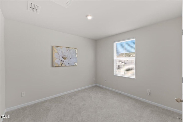 unfurnished room featuring baseboards, attic access, visible vents, and light colored carpet