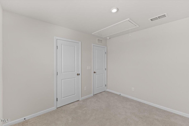 empty room featuring attic access, visible vents, baseboards, and light colored carpet