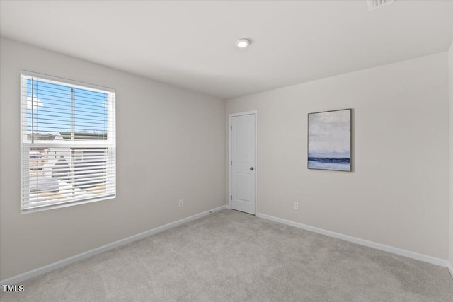 empty room featuring light carpet and baseboards