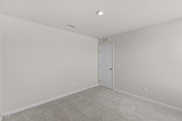 spare room with light colored carpet, visible vents, and baseboards