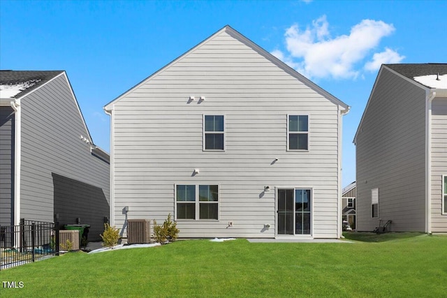 rear view of property with central air condition unit, fence, and a lawn