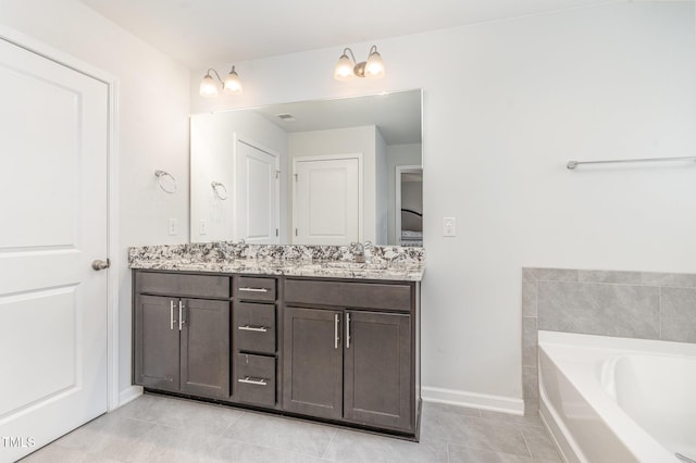 bathroom with a garden tub, double vanity, a sink, baseboards, and tile patterned floors