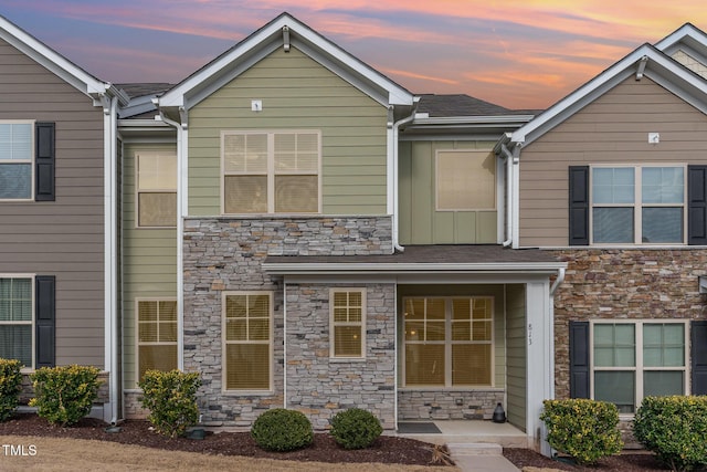 townhome / multi-family property featuring covered porch and stone siding