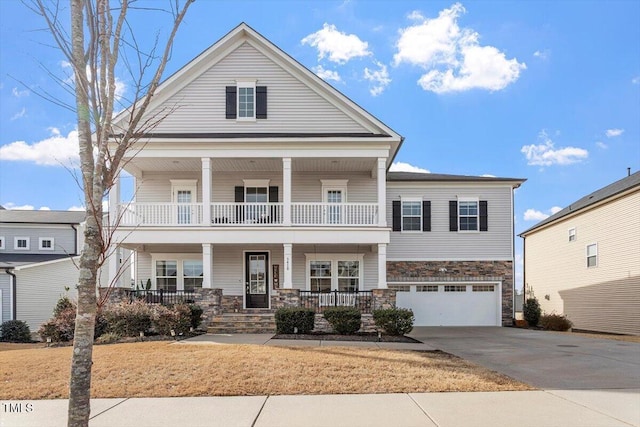 view of front of house with a balcony, covered porch, a garage, stone siding, and concrete driveway