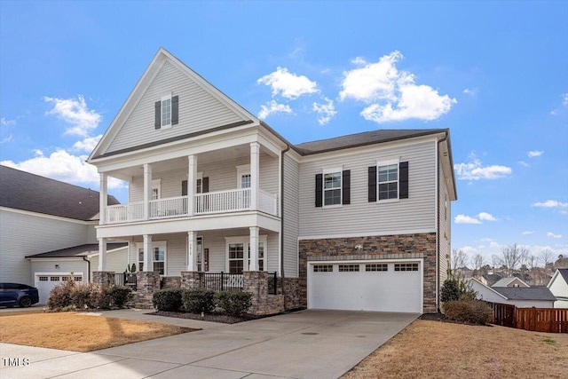 view of front of home featuring a garage, concrete driveway, a balcony, stone siding, and a porch