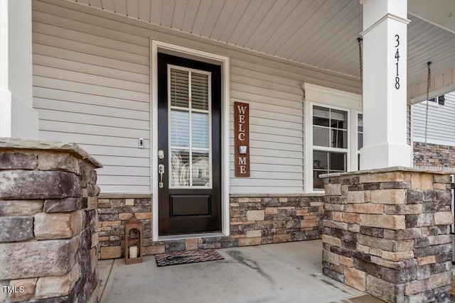 doorway to property with stone siding and a porch