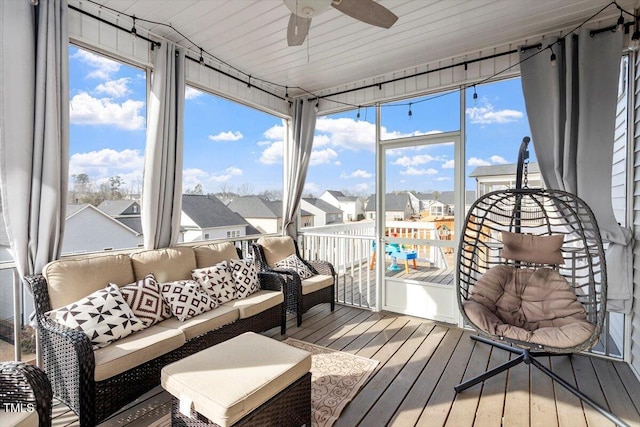 sunroom with ceiling fan, a residential view, and a healthy amount of sunlight