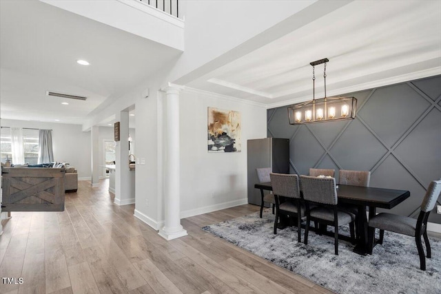 dining area with light wood-style floors, baseboards, visible vents, and ornate columns