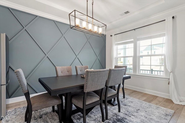 dining space with light wood finished floors, visible vents, baseboards, crown molding, and a notable chandelier