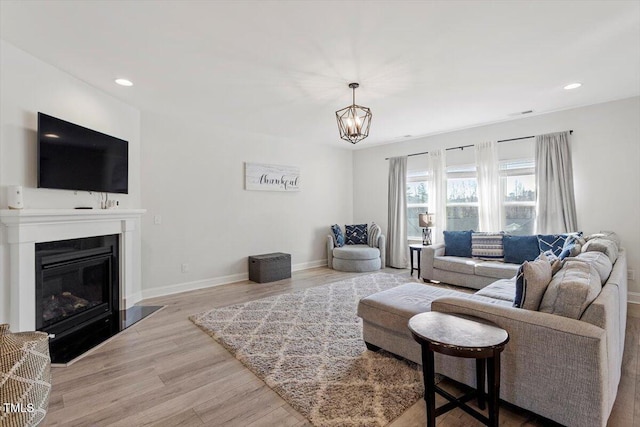 living room with wood finished floors, recessed lighting, a glass covered fireplace, and baseboards