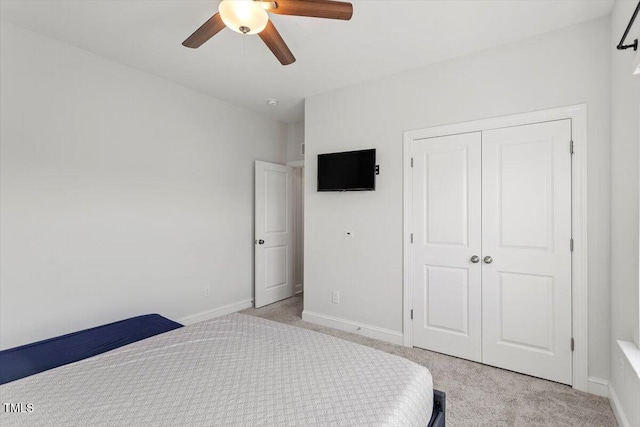 bedroom with light carpet, ceiling fan, a closet, and baseboards