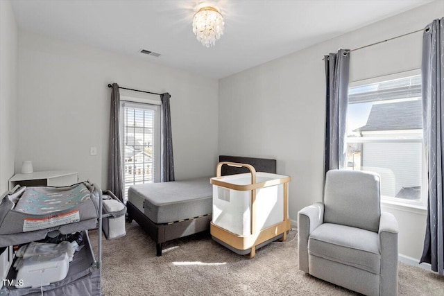 carpeted bedroom featuring visible vents and a notable chandelier