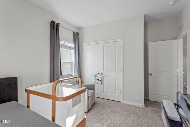 bedroom with a closet, light colored carpet, visible vents, and baseboards