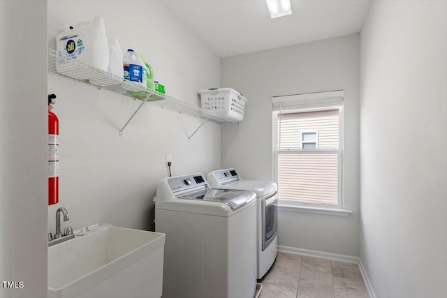 clothes washing area featuring washing machine and clothes dryer, light tile patterned floors, a sink, laundry area, and baseboards