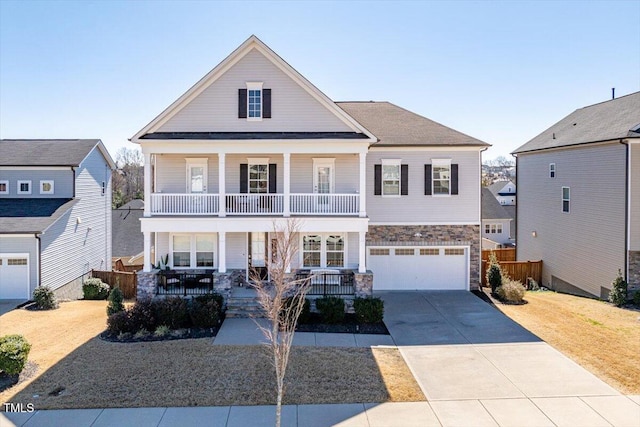 view of front of home with driveway, a balcony, stone siding, an attached garage, and covered porch