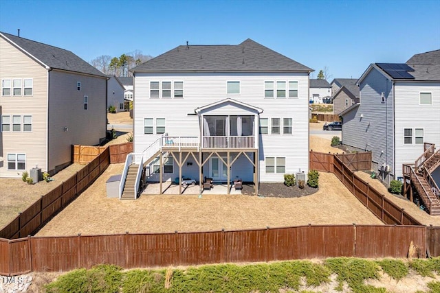 rear view of property with cooling unit, a sunroom, a residential view, a fenced backyard, and stairs