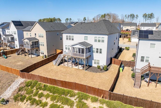 rear view of property with a sunroom, a patio area, a residential view, a fenced backyard, and stairs