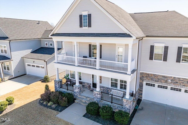 view of front of home with driveway, a porch, stone siding, and a balcony