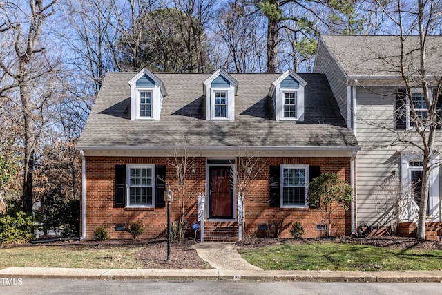 cape cod-style house with roof with shingles, brick siding, crawl space, and a front yard