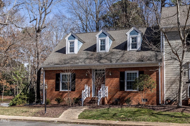 cape cod house with brick siding, a shingled roof, and a front yard