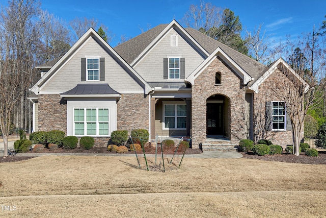 craftsman inspired home with a shingled roof, stone siding, metal roof, a standing seam roof, and a front lawn