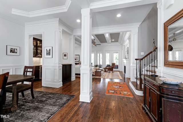 entrance foyer featuring ceiling fan, a decorative wall, stairs, dark wood finished floors, and ornate columns