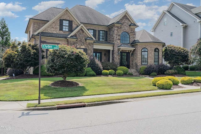 french provincial home featuring brick siding and a front lawn