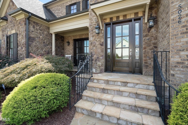 property entrance with covered porch and stone siding