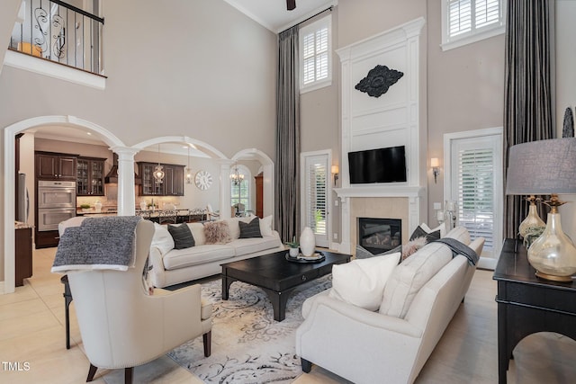 living room with arched walkways, a healthy amount of sunlight, a fireplace, and ornate columns